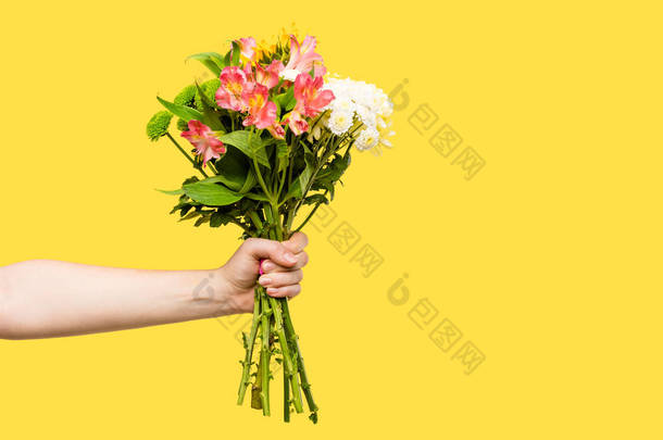 裁剪拍摄的人拿着美丽的花束的花孤立在黄色