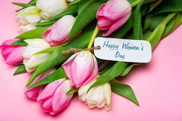 一束郁金香和带着快乐女人的纸标签，每天都在粉红的表面上刻着字母
