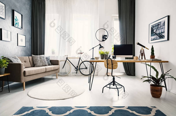 在明亮的<strong>公寓</strong>室内与棕色沙发和自行车办公桌上的植物和木椅。真实照片