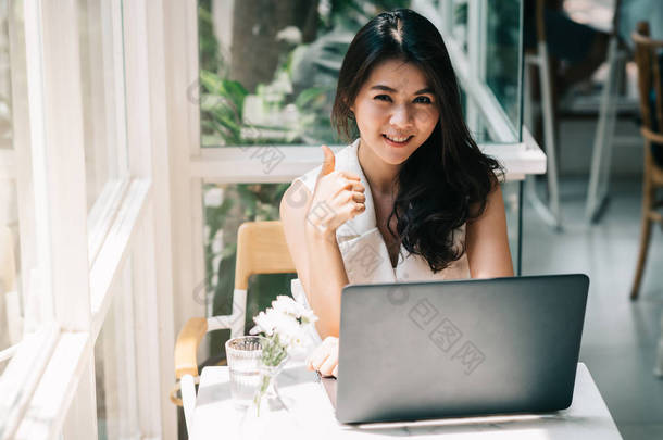 亚洲女人出现拇指同时使用笔记本电脑