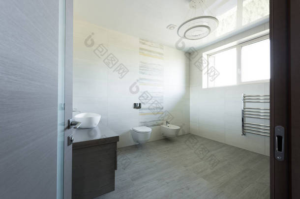 现代灰色卫生间的室内卫生间和坐浴盆, 从门看