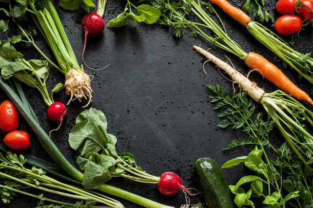 Young spring vegetables on black chalkboard