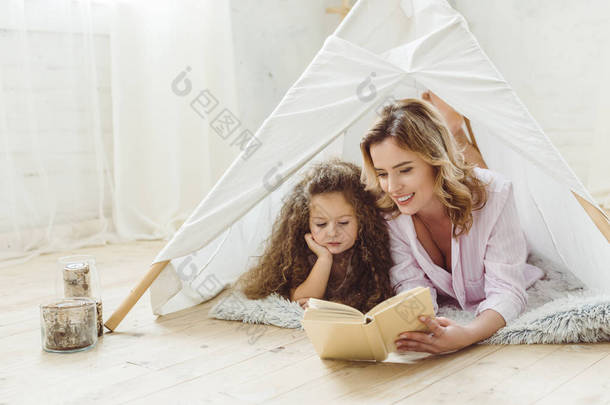 快乐的母亲和女儿一起读书在孩子窝棚