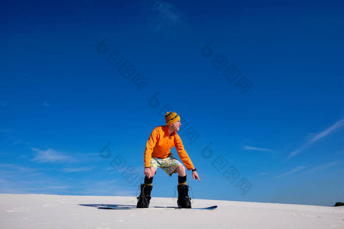 阳光明媚的日子, 沙漠中的沙子登入。滑稽的人准备跳跃, 而滑雪在沙丘上, 对蓝天。广角.