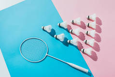 蓝色和粉红色纸上的羽毛球拍和羽毛球组合的顶部视图