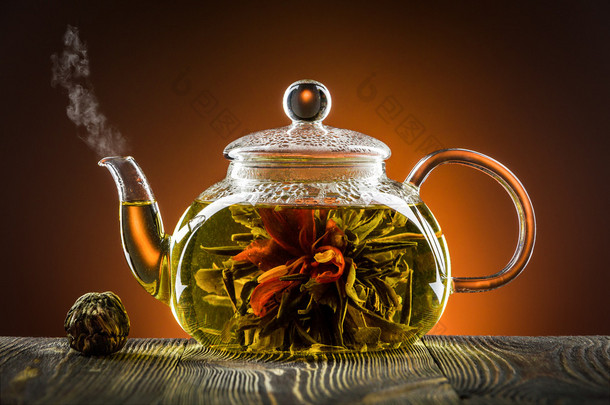 玻璃<strong>茶壶</strong>配茶花朵木制的桌子上