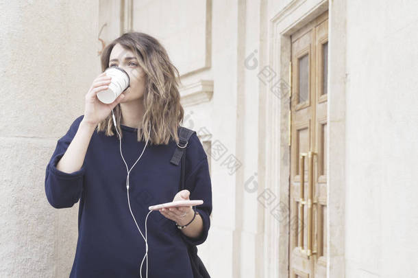 一个微笑的黑发白人女孩在外面听音乐