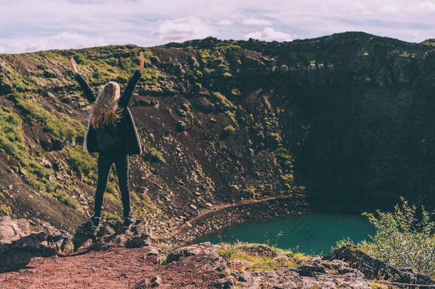 后面的女孩站在与举手和看美丽的火山口湖在冰岛