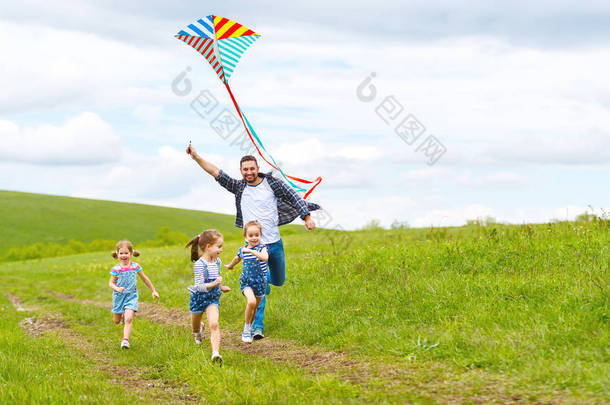 愉快的家庭父亲和孩子在草甸跑与风筝