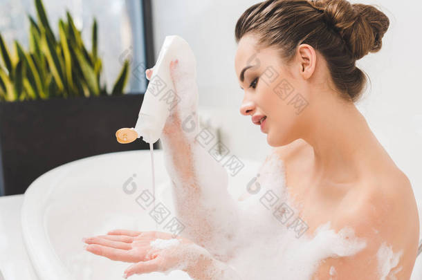 年轻女子<strong>沐浴</strong>用凝胶和泡沫的侧面图 