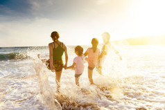 在日落时在沙滩上玩的快乐年轻家庭