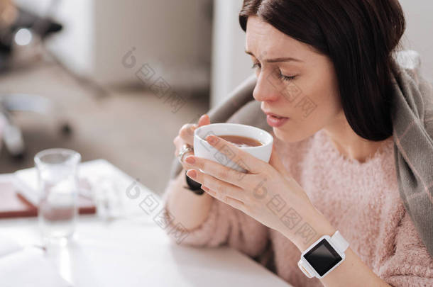 生病的女孩一边喝茶一边的肖像
