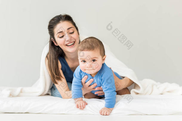 母亲与她的儿子在毯子下玩 