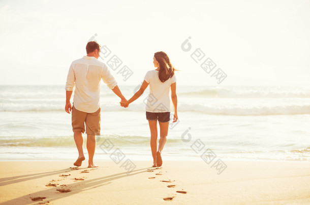 在日落时在沙滩上散步的情侣