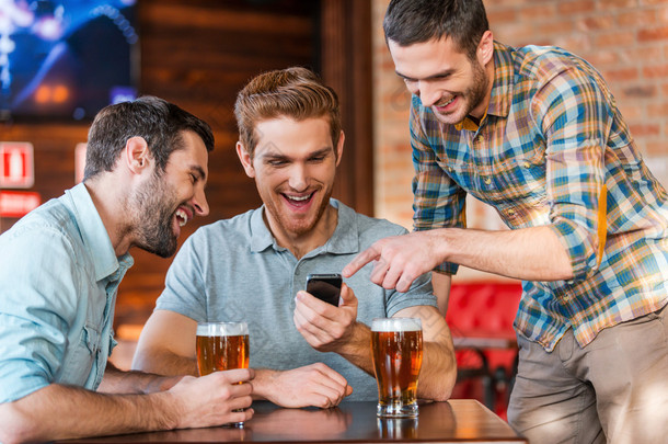 在智能手机的酒吧喝啤酒的男人