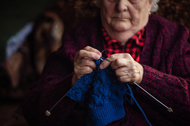 老妇人坐在家里和针织服装