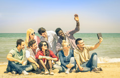 多种族快乐的朋友拍照的平板电脑以海滩-多种族概念的幸福和现代友谊一起反对种族主义为和平和乐趣-饱和筛选的复古