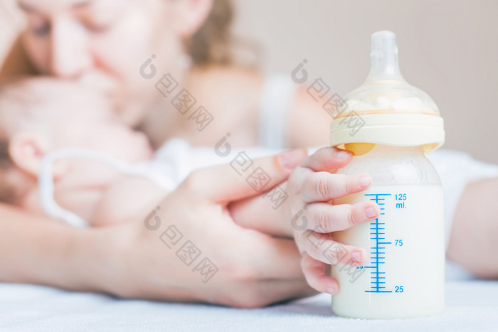 Baby holding a baby bottle with breast milk