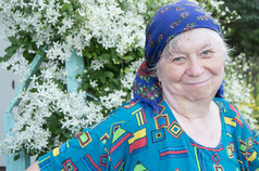 在你的花园的白色花朵背景的头巾微笑的老年妇女