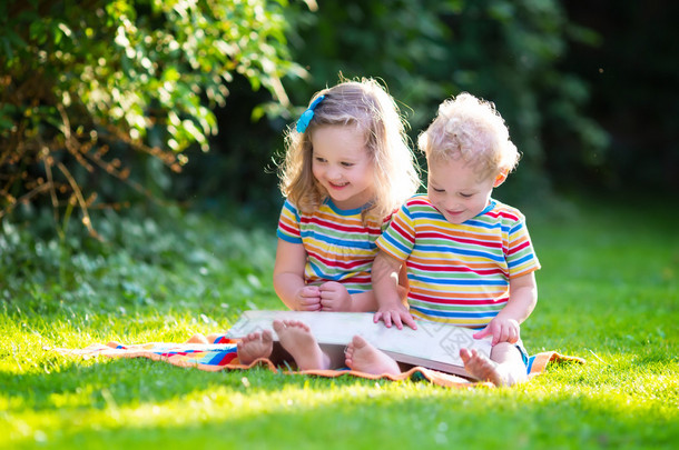 两个孩子在夏天花园里看书