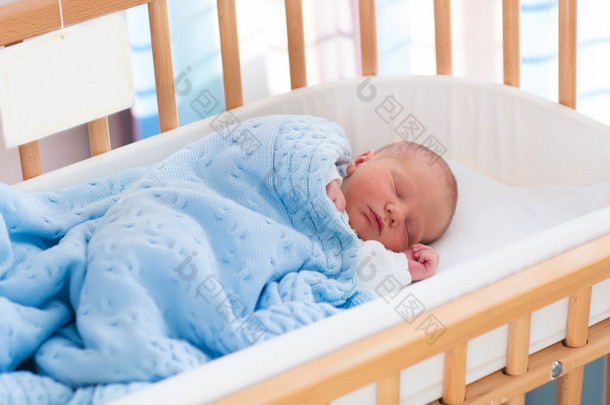 Newborn baby boy in hospital cot