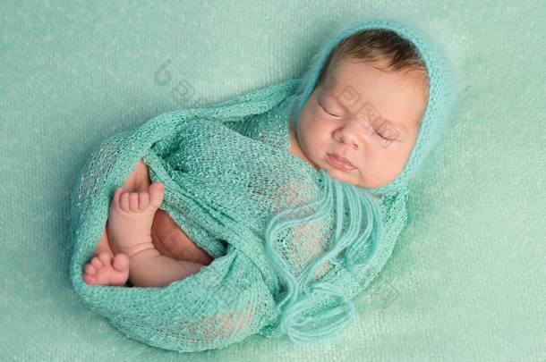 搞笑睡觉新生儿在蓝色毯子和尿布