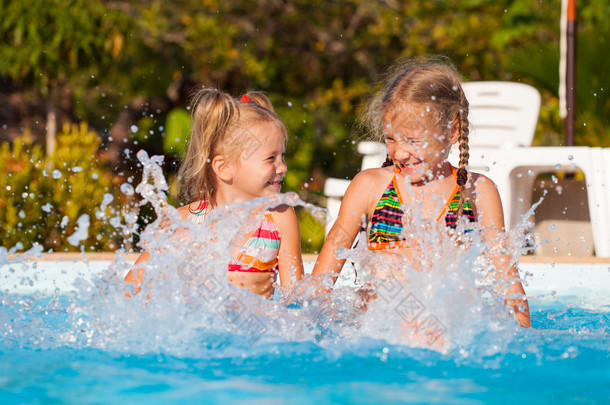 两个快乐的小女孩在游泳池周围溅