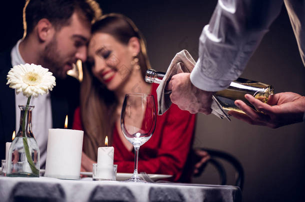 服务员倒酒, 而美丽的情侣在情人节在餐厅浪漫的约会