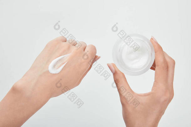 裁剪视图的妇女与奶油在手和皮肤隔离在白色