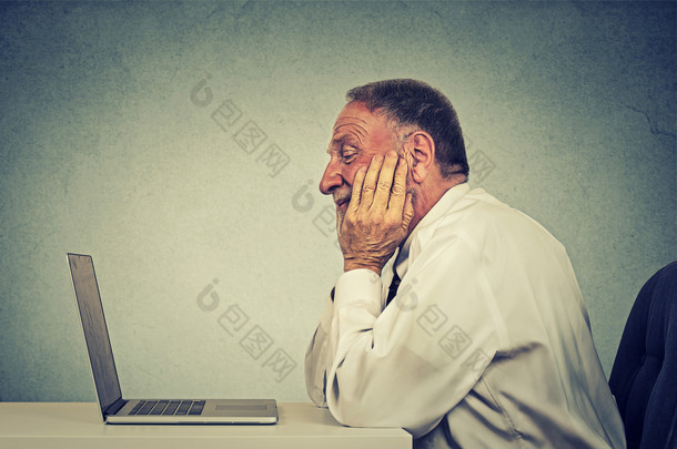 老人使用手提电脑阅读电子邮件消息。电子学习概念 