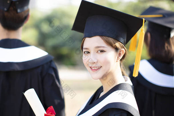 微笑的年轻女子在毕业时显示她的文凭