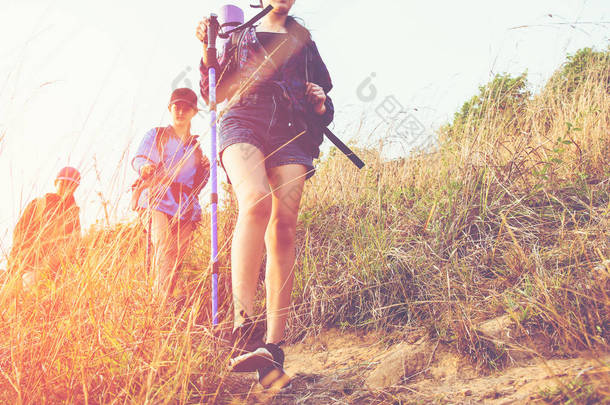 在日落时分, 一群徒步旅行者带着背包走在山上的年轻女子。旅行者去野营。<strong>旅游</strong>理念