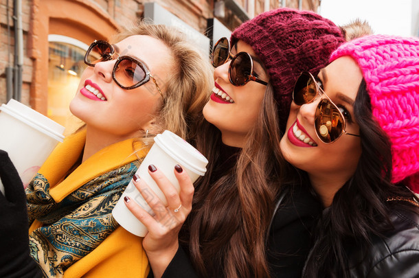 关闭了喝咖啡的三个年轻开朗漂亮女孩朋友的画像。微笑着，去购物，.