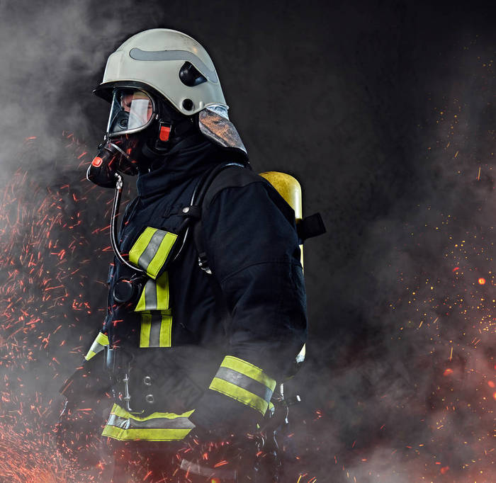 一名职业消防员身着制服和氧气面罩站在火灾