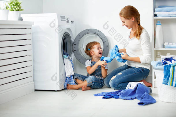 家庭的母亲和儿童女孩在洗衣房附近洗机