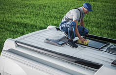 40多岁的白人男子用海绵和软洗涤剂清洁营房房顶安装了太阳能电池板。汽车家庭维修。RV工业主题.