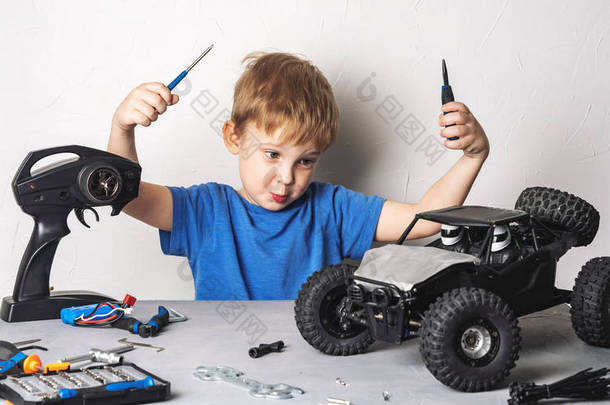 穿着蓝色T恤的小男孩正在修理他的RC车.