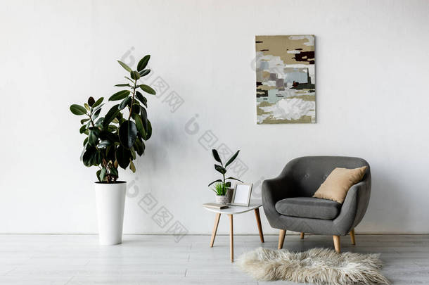 茶几旁边的灰色扶手椅，有绿色的植物和<strong>现代客厅</strong>的框架 