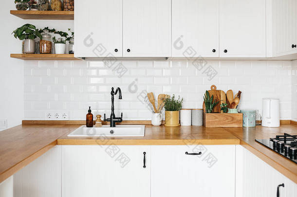 从<strong>现代风格</strong>看白色厨房，厨房细节，木制桌子上的植物，白色瓷砖墙背景。可持续生活生态友好型厨房