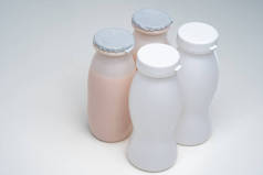 发酵牛奶产品。健康食品。有健康酸奶的酒瓶。用于维持健康的产品。牛奶洒在白桌子上.