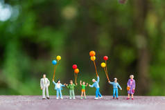 微型人：快乐家庭手持五颜六色的气球 