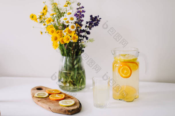 夏天的概念。野生自然花卉的花束。自制柠檬水与<strong>橙子</strong>和柠檬。健康的<strong>新鲜</strong>冷饮 