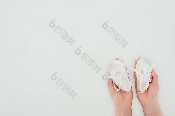 裁剪图像的妇女持有白色婴儿鞋隔离白色