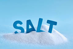 溢出的盐和蓝色字母的特写照片在蓝色背景上拼写单词盐
