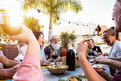 日落时分，快乐的家庭在户外聚餐——一群不同的朋友在享受美食