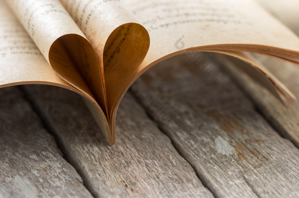 木质背景上打开的书页的心形。