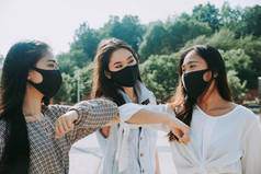 在大流行病和社会距离时代，戴口罩的亚洲女孩在室外粘合- -检疫、预防和护理的概念