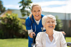 快乐的护士和坐在轮椅上享受户外治疗的老年妇女。美丽的怒族