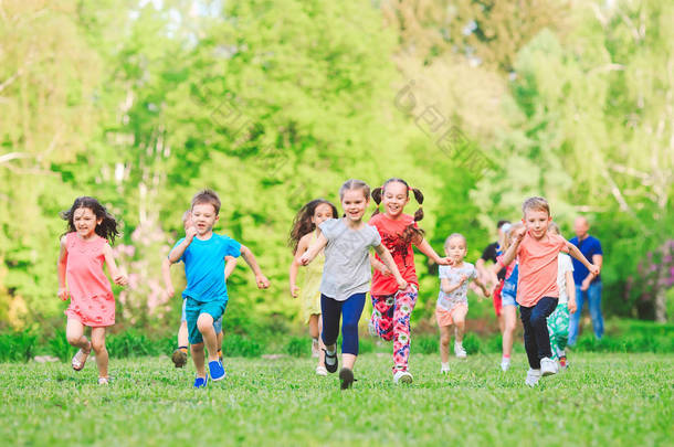 许多不同的孩子，男孩和女孩在阳光明媚的夏日穿着休闲服在公园里跑步。