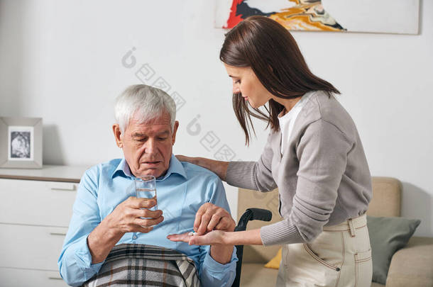 年幼的成年女儿在中风后照顾他的时候给年长的父亲吃药